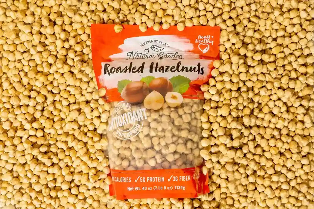 Nature’s Garden Roasted Hazelnuts snack pack placed on a background of loose hazelnuts for healthy snacking appeal.