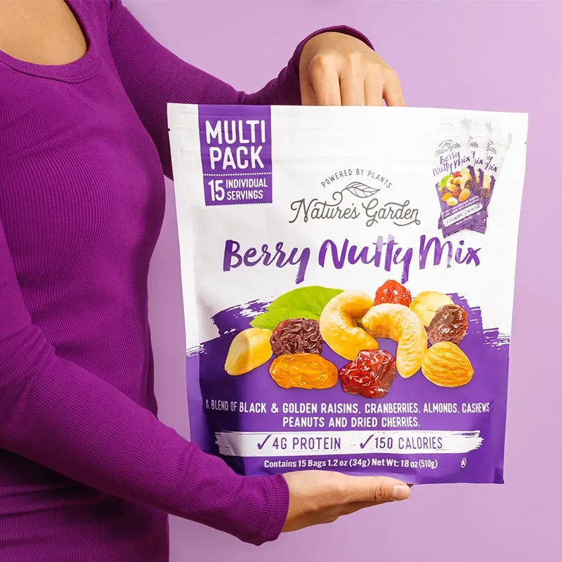 Person holding a bag of Nature's Garden Berry Nutty Mix, a snack blend of dried berries, nuts, and raisins with 4g protein and 150 calories per serving.