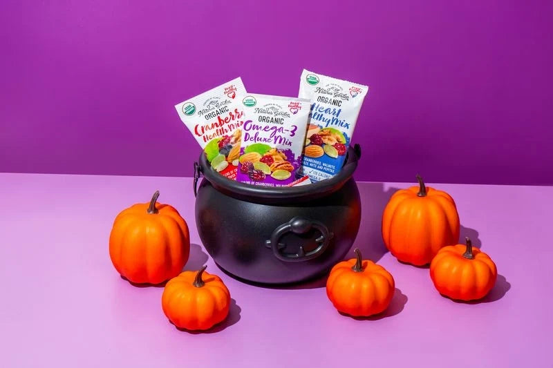 Nature's Garden organic trail mix snack packs in a Halloween cauldron surrounded by pumpkins