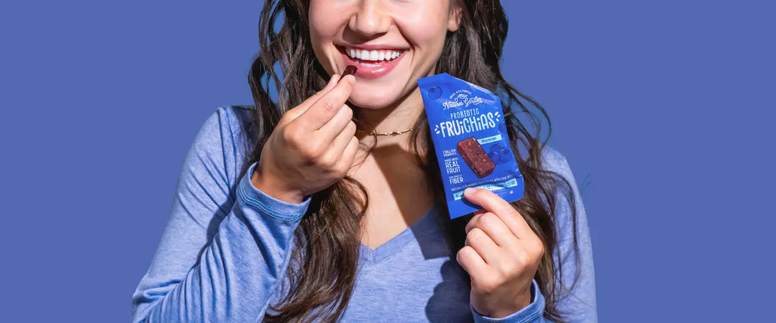 Smiling woman enjoying Nature’s Garden Probiotic Blueberry FruiChias snack bar in USA, made with real fruit, fiber, and probiotics.