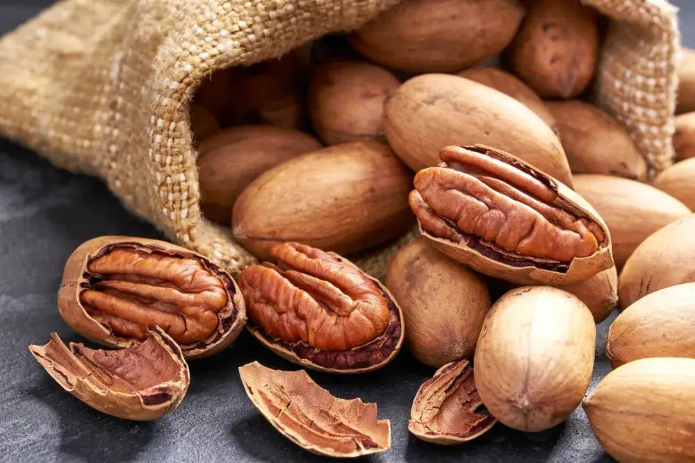Close-up of cracked pecans spilling from a burlap sack, showcasing their rich texture and natural nutty goodness.