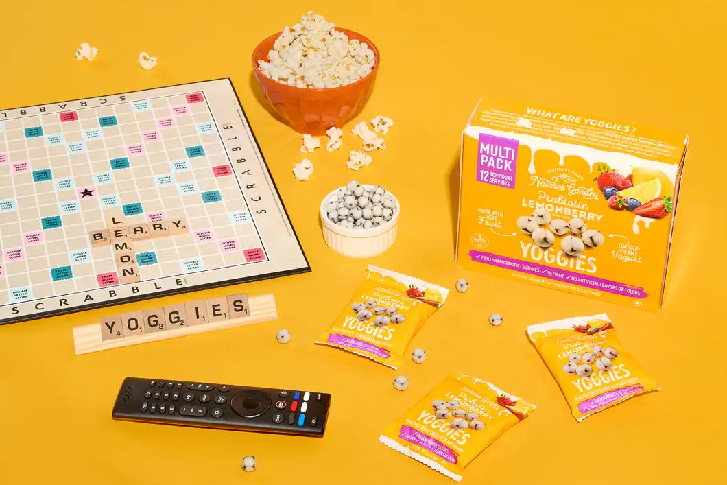 Nature’s Garden Probiotic Lemonberry Yoggies snack multi-pack in USA game night scene with Scrabble, popcorn, and yogurt bites.