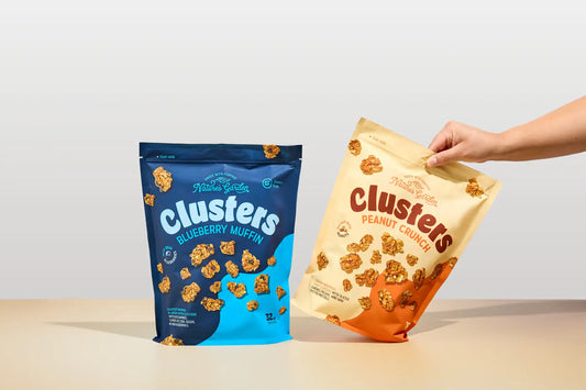 Nature’s Garden Clusters – Blueberry Muffin and Peanut Crunch snack bags on display, showing crunchy granola-style clusters made with nuts, seeds, and fruit for on-the-go snacking.