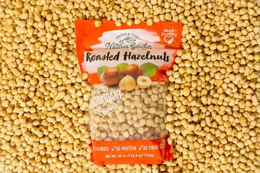 Nature’s Garden Roasted Hazelnuts snack pack placed on a background of loose hazelnuts for healthy snacking appeal.