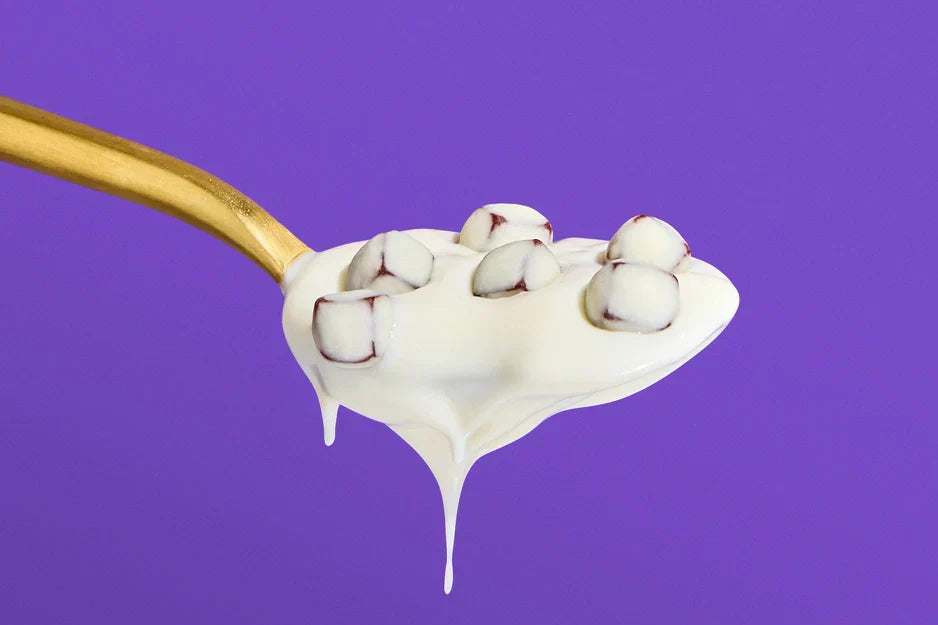 Spoonful of creamy yogurt with Probiotic Yoggies fruit bites against a vibrant purple background, showcasing a fun functional snack.