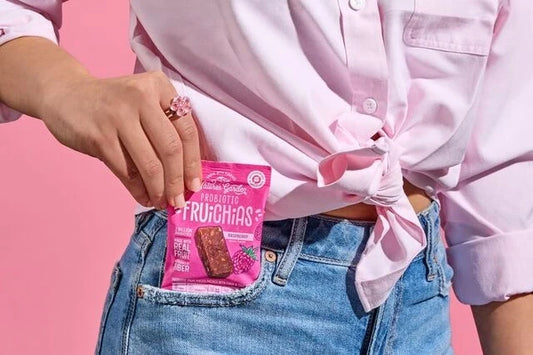 Nature’s Garden Probiotic FRUiCHiAS fruit snack pack held by a woman against a pink background.