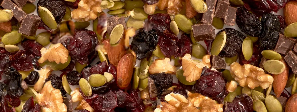 Close-up of Nature’s Garden heart healthy trail mix with walnuts, almonds, cranberries, pepitas, prunes, and dark chocolate.