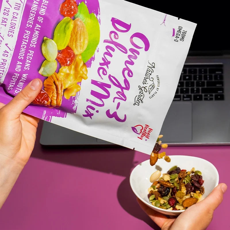 Pouring Nature’s Garden Omega-3 Deluxe Mix into a bowl—heart-healthy trail mix with almonds, cranberries, and pumpkin seeds