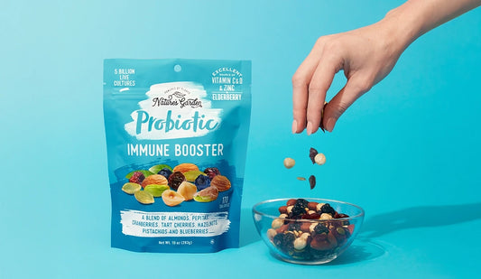 Nature’s Garden Probiotic Immune Booster mix with nuts, berries, and seeds being poured into a bowl against a blue backdrop.